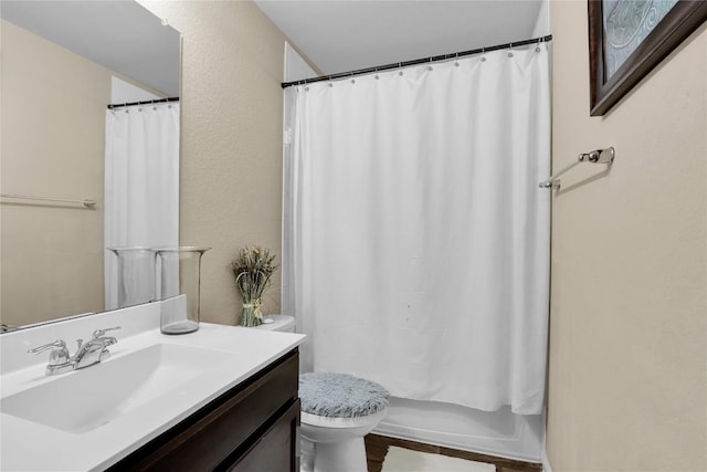 bathroom featuring shower / tub combo with curtain, toilet, vanity, and a textured wall