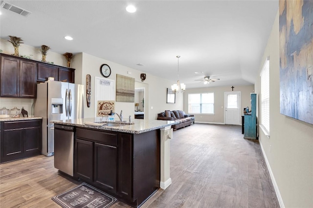 kitchen featuring visible vents, a sink, light stone counters, dark brown cabinets, and dishwasher