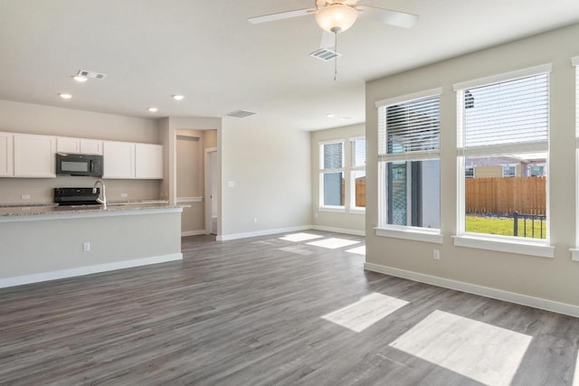 unfurnished living room with baseboards, visible vents, and a wealth of natural light