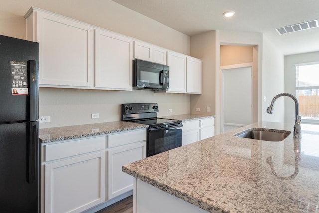 kitchen with visible vents, white cabinets, black appliances, and a sink