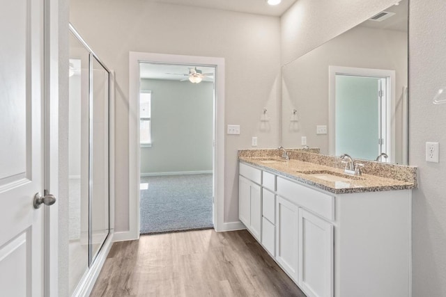 full bath with a shower stall, wood finished floors, double vanity, and a sink