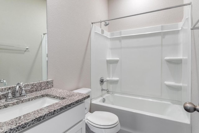 bathroom featuring tub / shower combination, toilet, vanity, and a textured wall