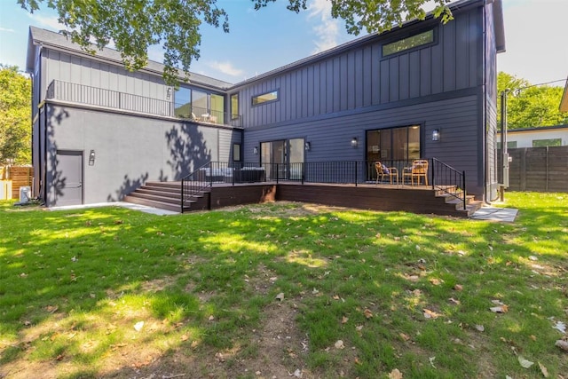 rear view of property with a wooden deck, board and batten siding, and fence