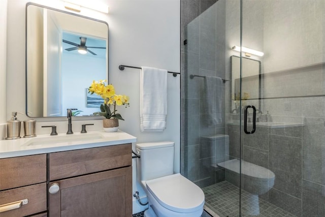 full bathroom with a stall shower, toilet, vanity, and a ceiling fan