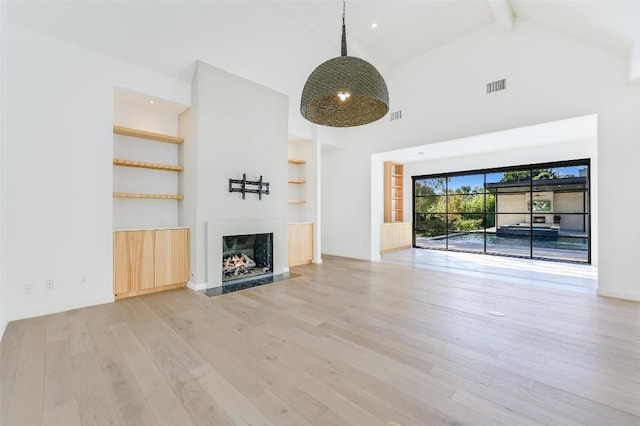 unfurnished living room featuring light wood-style flooring, a fireplace with flush hearth, visible vents, and built in features