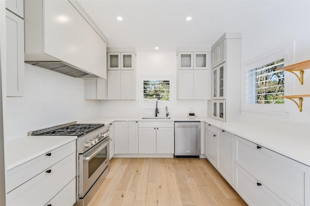 kitchen with open shelves, a sink, stainless steel appliances, custom range hood, and white cabinetry