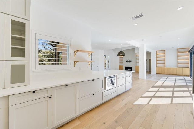 kitchen featuring open shelves, light countertops, recessed lighting, and light wood finished floors