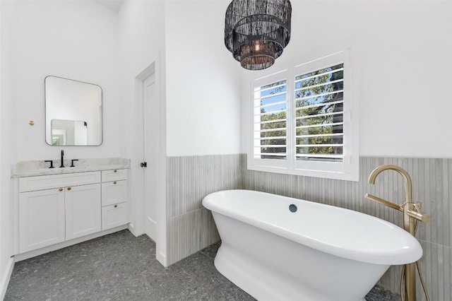 bathroom with vanity, a freestanding tub, and a wainscoted wall