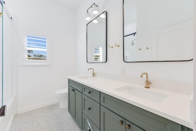 full bath with a sink, baseboards, toilet, and double vanity