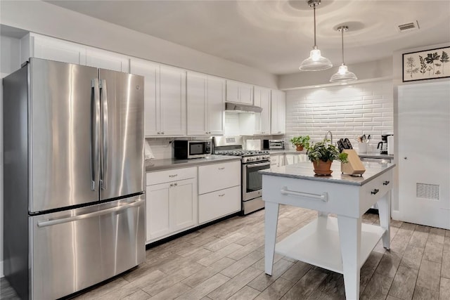 kitchen with under cabinet range hood, visible vents, appliances with stainless steel finishes, and wood finish floors