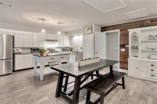 kitchen with visible vents, under cabinet range hood, appliances with stainless steel finishes, light wood-style floors, and white cabinets