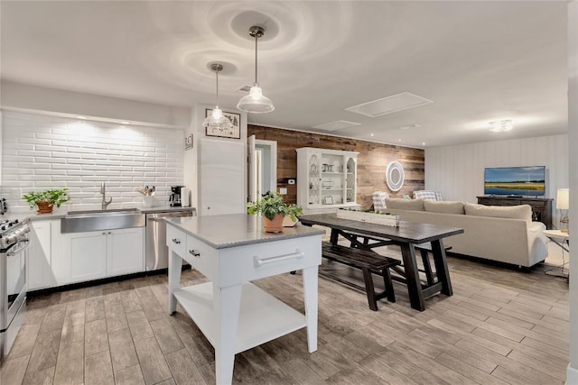 kitchen featuring a sink, light wood-style floors, appliances with stainless steel finishes, white cabinetry, and open floor plan