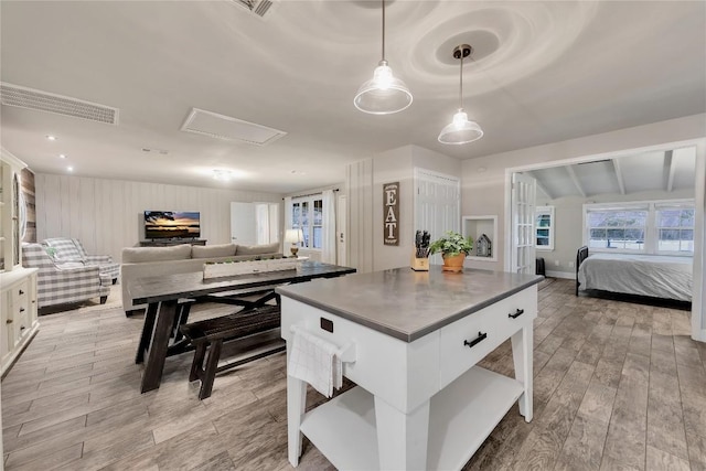 kitchen with dark countertops, a center island, open floor plan, pendant lighting, and light wood-type flooring