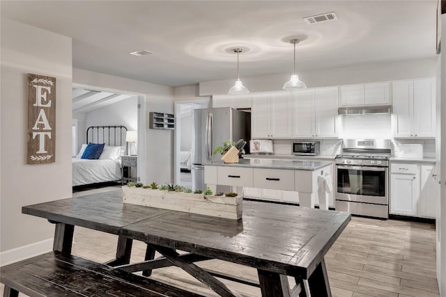 kitchen with tasteful backsplash, visible vents, light wood-style floors, white cabinets, and stainless steel appliances