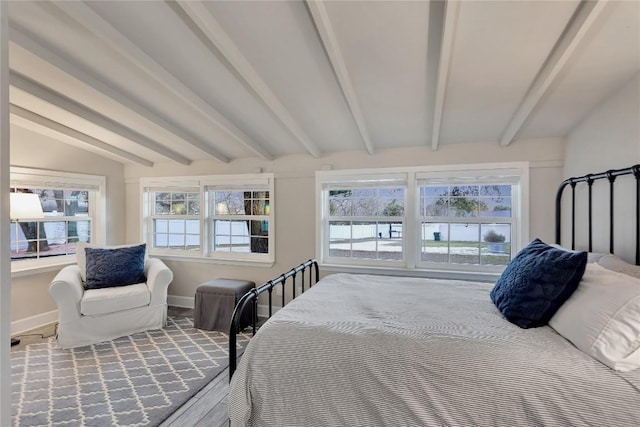 bedroom featuring multiple windows, baseboards, and vaulted ceiling with beams