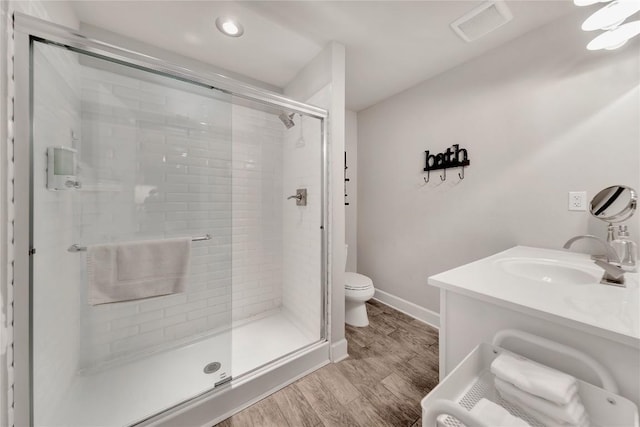 bathroom with vanity, wood finished floors, visible vents, a shower stall, and toilet