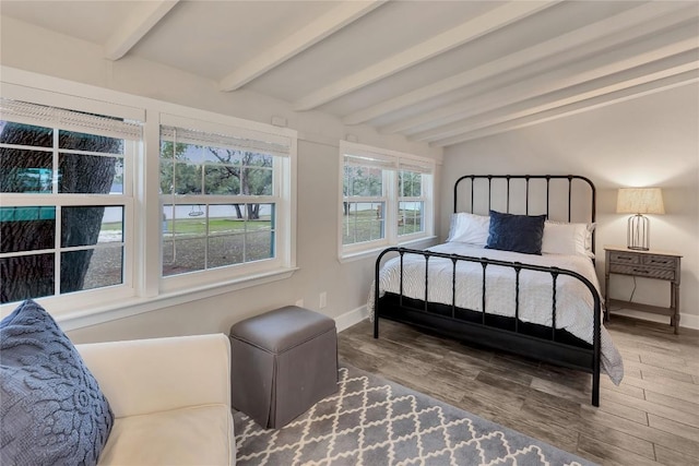 bedroom with beamed ceiling, baseboards, and wood finished floors