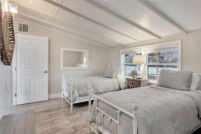 bedroom featuring visible vents, vaulted ceiling with beams, light wood-type flooring, and baseboards