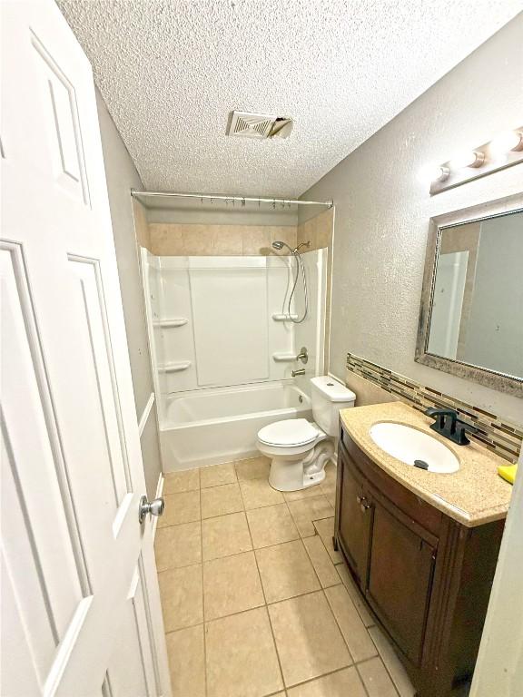 full bath with tile patterned flooring, visible vents, tub / shower combination, toilet, and a textured ceiling