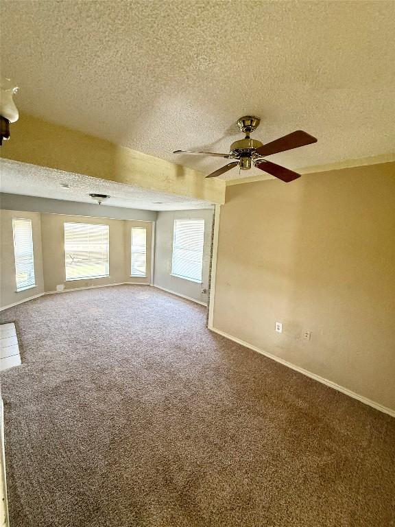 carpeted spare room with a textured ceiling, baseboards, and a ceiling fan