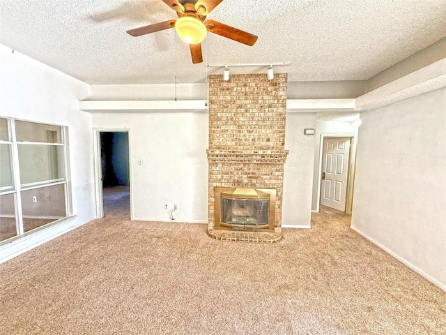 unfurnished living room featuring a brick fireplace, a textured ceiling, baseboards, and carpet floors