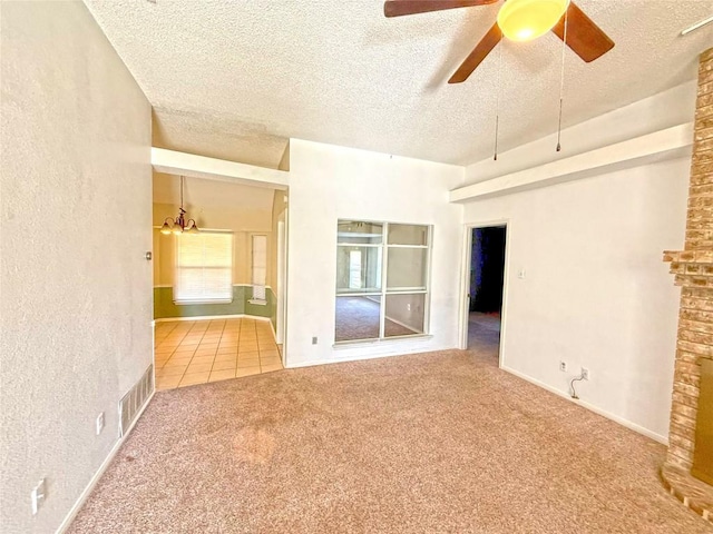 carpeted spare room with a ceiling fan, visible vents, a textured wall, and a textured ceiling