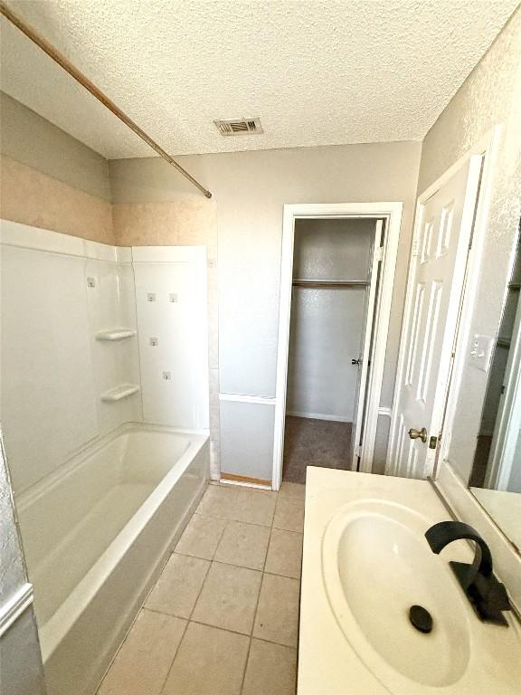 bathroom featuring a textured ceiling, visible vents, mail area, shower / washtub combination, and tile patterned floors