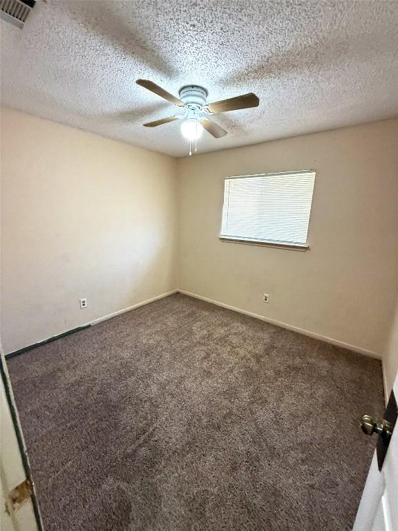 carpeted empty room with baseboards, visible vents, a textured ceiling, and ceiling fan