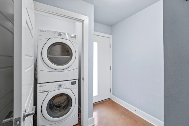 clothes washing area featuring laundry area, baseboards, and stacked washer and dryer