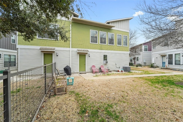 back of property with central AC unit, fence, and a lawn