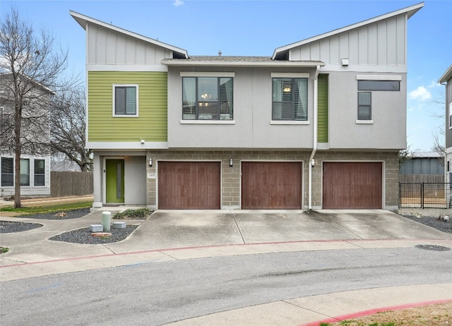 multi unit property with board and batten siding, concrete driveway, an attached garage, and fence