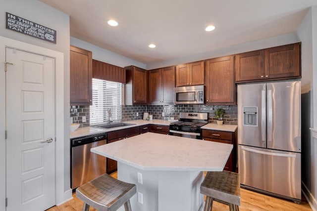 kitchen featuring a breakfast bar area, a kitchen island, a sink, stainless steel appliances, and tasteful backsplash