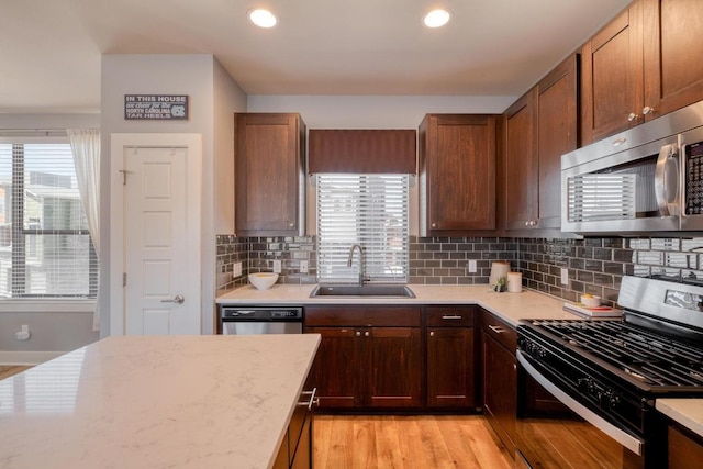 kitchen with a wealth of natural light, stainless steel appliances, light wood-style floors, and a sink