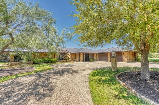 view of front of house with metal roof, an attached garage, and driveway