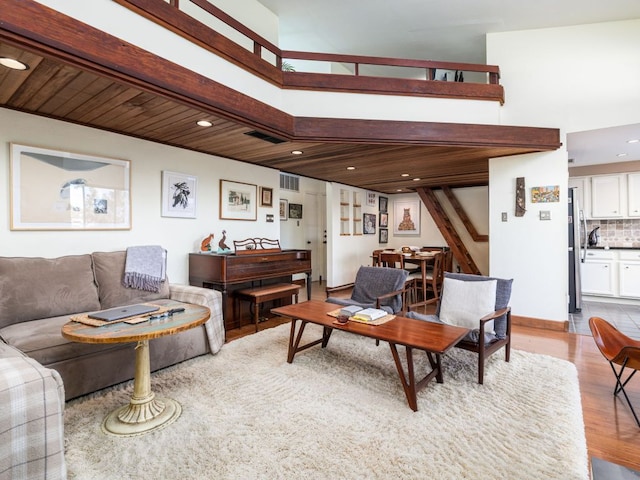 living room featuring recessed lighting, visible vents, wood finished floors, and a towering ceiling