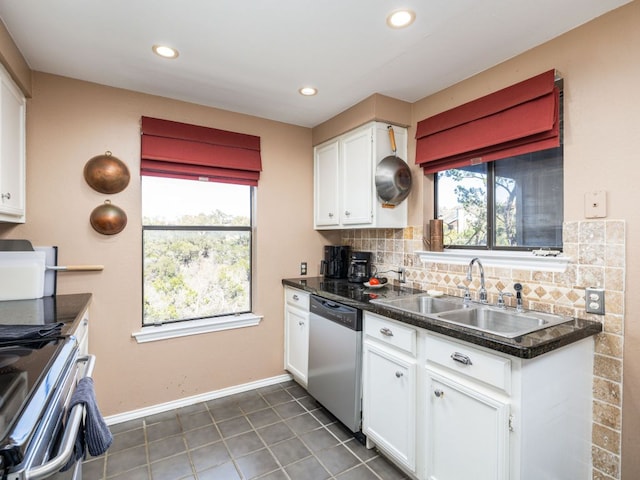 kitchen featuring plenty of natural light, a sink, decorative backsplash, stainless steel dishwasher, and dark countertops