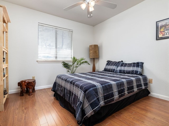 bedroom featuring baseboards, wood finished floors, and a ceiling fan