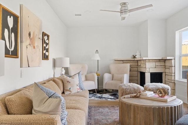 living room with a ceiling fan, wood finished floors, a fireplace, and visible vents