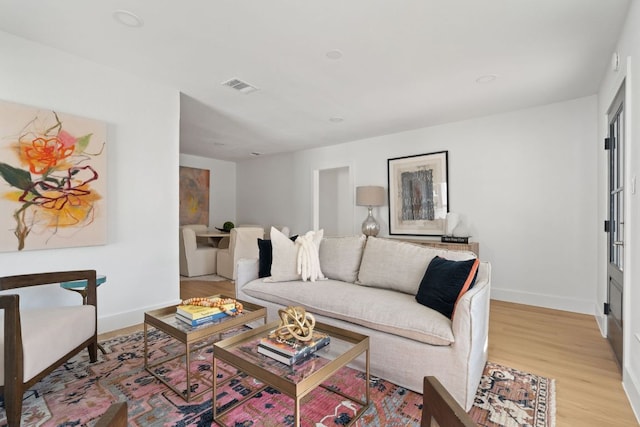 living room with visible vents, baseboards, and light wood-style flooring