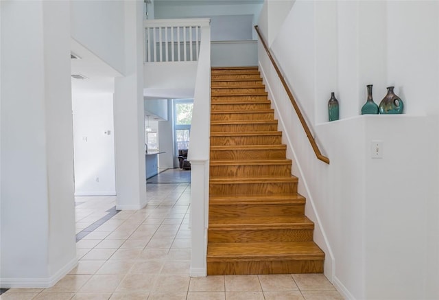 stairs featuring tile patterned floors, a high ceiling, and baseboards