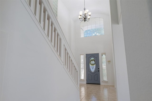 foyer entrance featuring light tile patterned floors, a notable chandelier, a healthy amount of sunlight, and stairs