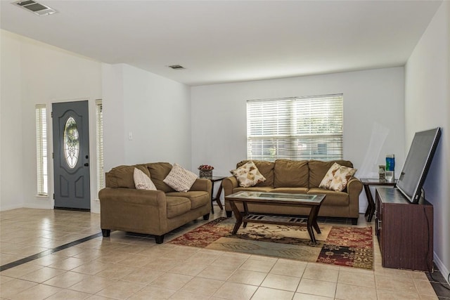 living room with light tile patterned floors, visible vents, and baseboards