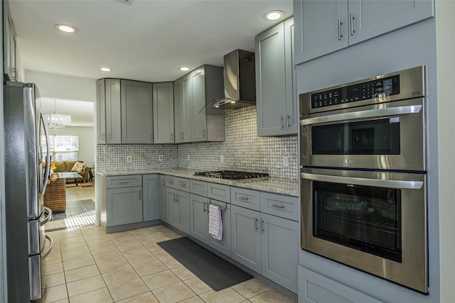 kitchen featuring gray cabinets, appliances with stainless steel finishes, and wall chimney range hood