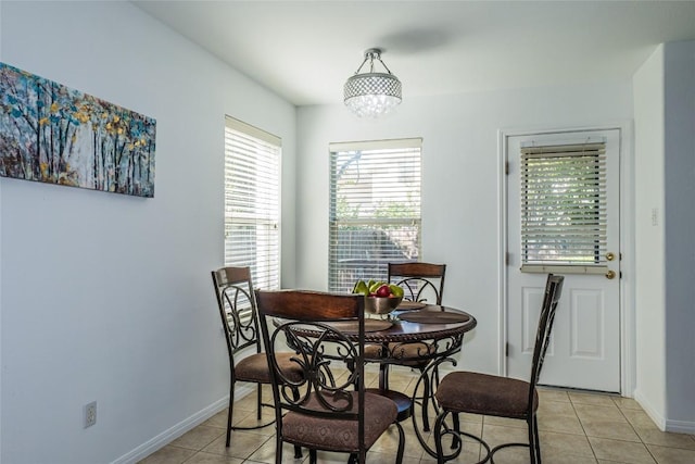 dining area with light tile patterned floors, baseboards, and a chandelier