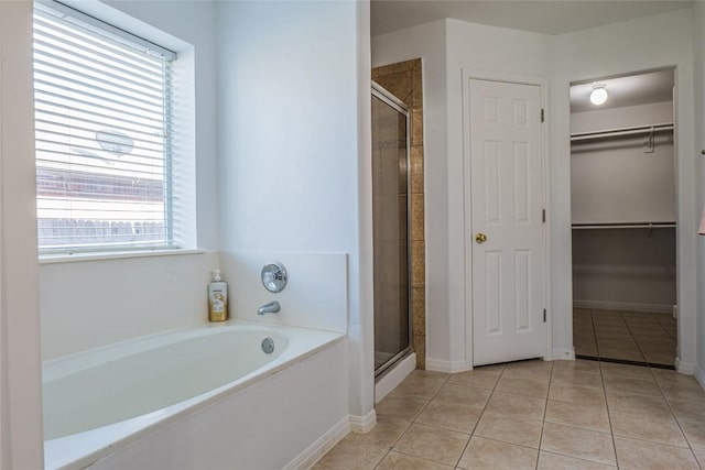 full bathroom with tile patterned floors, a shower stall, a bath, and a walk in closet