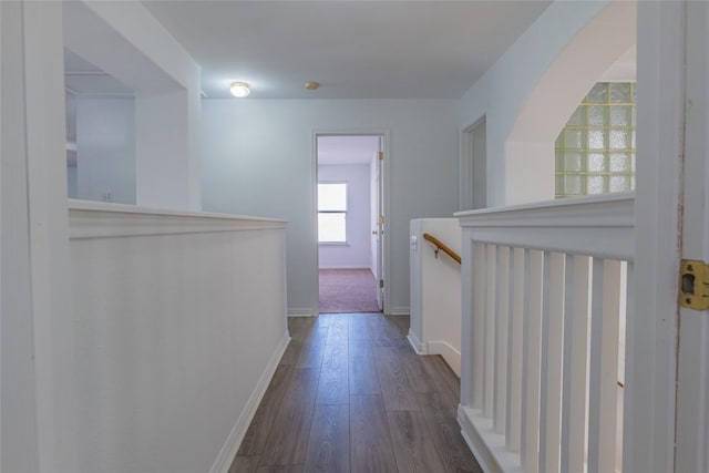 hall with an upstairs landing, baseboards, and wood finished floors