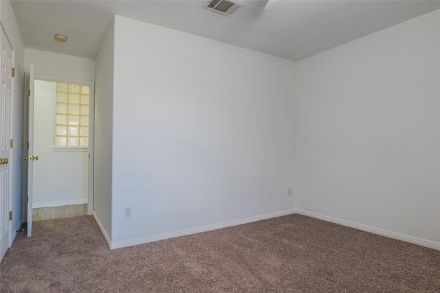 empty room featuring carpet, visible vents, and baseboards