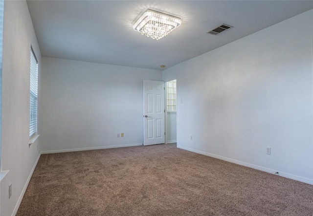 unfurnished room with carpet, visible vents, and baseboards