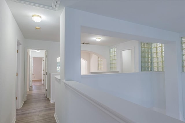 corridor featuring wood finished floors, visible vents, and baseboards