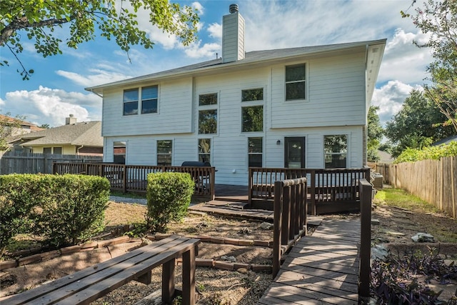 back of property featuring a wooden deck, a chimney, and fence